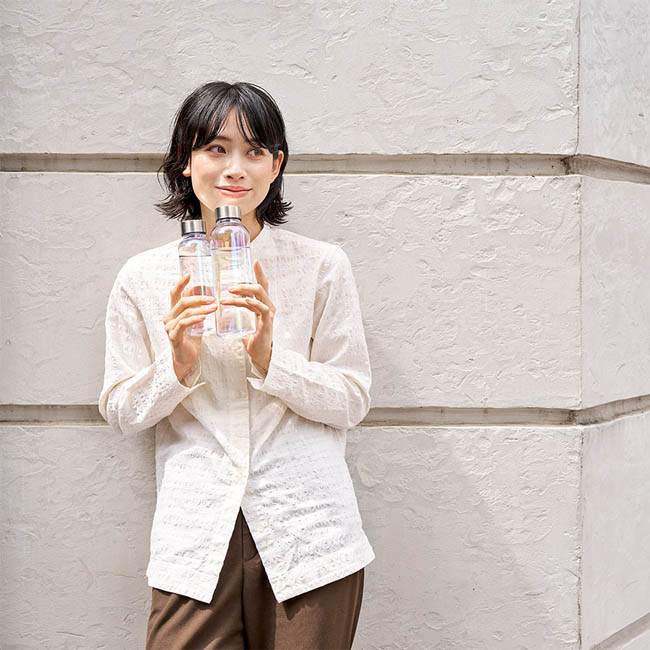 オーロラクリアボトル570ｍｌ　クリア（SNS-0301001）　壁を背景に2本のボトルを持つ女性