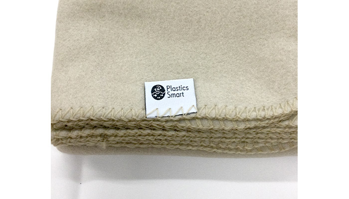 ベルト付き再生PETブランケット(SNS-0600951)「プラスチック・スマート」に貢献していることを示すロゴタグ付き